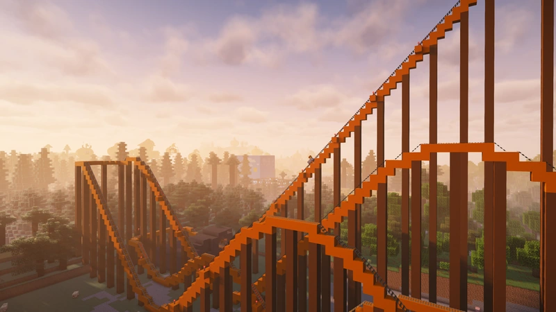 Orange Pumpkin Coaster tracks rise and dip above the autumn trees at sunset.